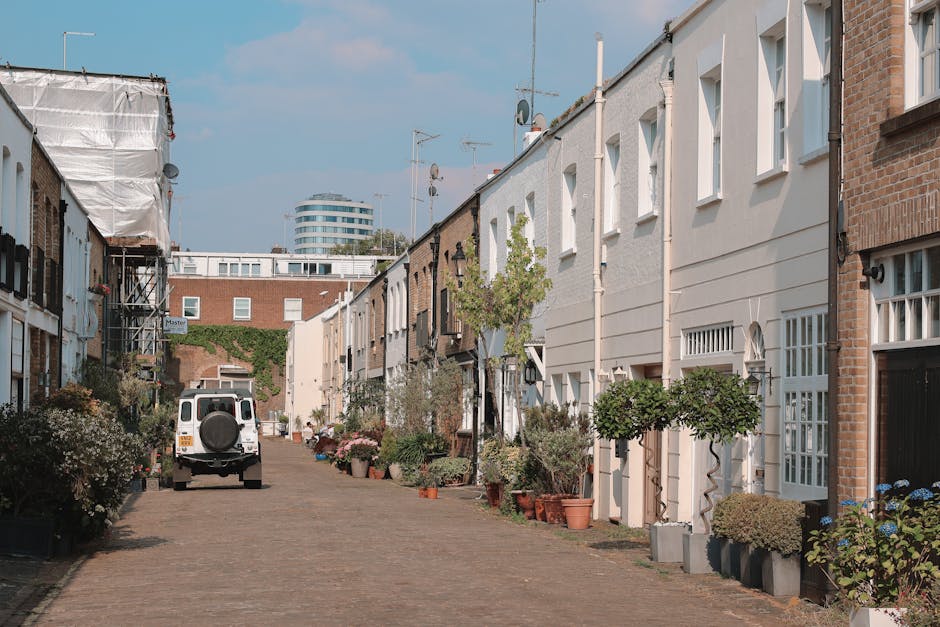 A street scene outside a property featuring an alleyway with a man wearing casual clothes and sunglasses walking by. In the foreground, there are black and white patterned panel fences and a door set